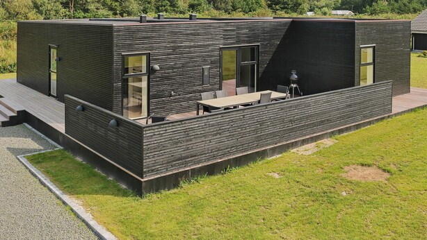 A modern building with a flat roof, large windows, and a patio area with outdoor seating. - Stylish Holiday Home in Jutland near Baltic Sea Beach (Hadsund)