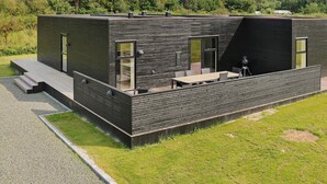 A modern, single-story building with a flat roof, large windows, and a patio area with outdoor seating. - Stylish Holiday Home in Jutland near Baltic Sea Beach (Hadsund)