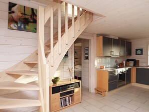 A modern kitchen with wooden cabinets, a built-in oven, and a small island.