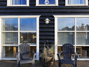 A log cabin with a deck, two chairs, and a potted plant. - 5 Star Holiday Home in Skagen (Skagen)