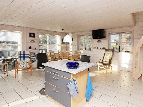 A spacious kitchen with a central island, wooden cabinets, and a dining area with chairs.