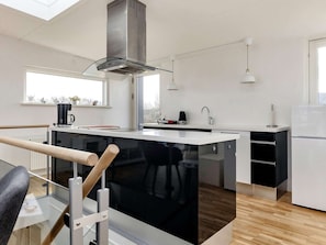 A modern kitchen with a central island, a stainless steel range hood, and pendant lighting.