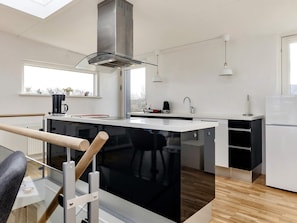 A modern kitchen with a central island, stainless steel appliances, and a window providing natural light. - 5 Person Holiday Home in Stege (Stege)