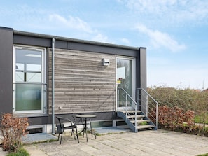 A modern building with a grey exterior, large windows, and a staircase leading to a balcony. - 5 Person Holiday Home in Stege (Stege)