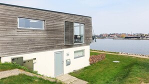 Un edificio moderno con techo inclinado, amplias ventanas y vista a un cuerpo de agua.