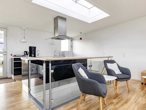 Een moderne keuken met dakraam, een eethoek met twee stoelen en uitzicht op de omgeving.