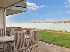 A patio with a table and chairs overlooking a body of water. - 5 Person Holiday Home in Stege (Stege)