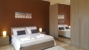 Ett hotellrum med en säng, sänglampor, en spegel och en tavla på väggen.