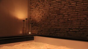 A bathtub with a brick wall behind it. - Palau Macelli (Castello d'Empuries)