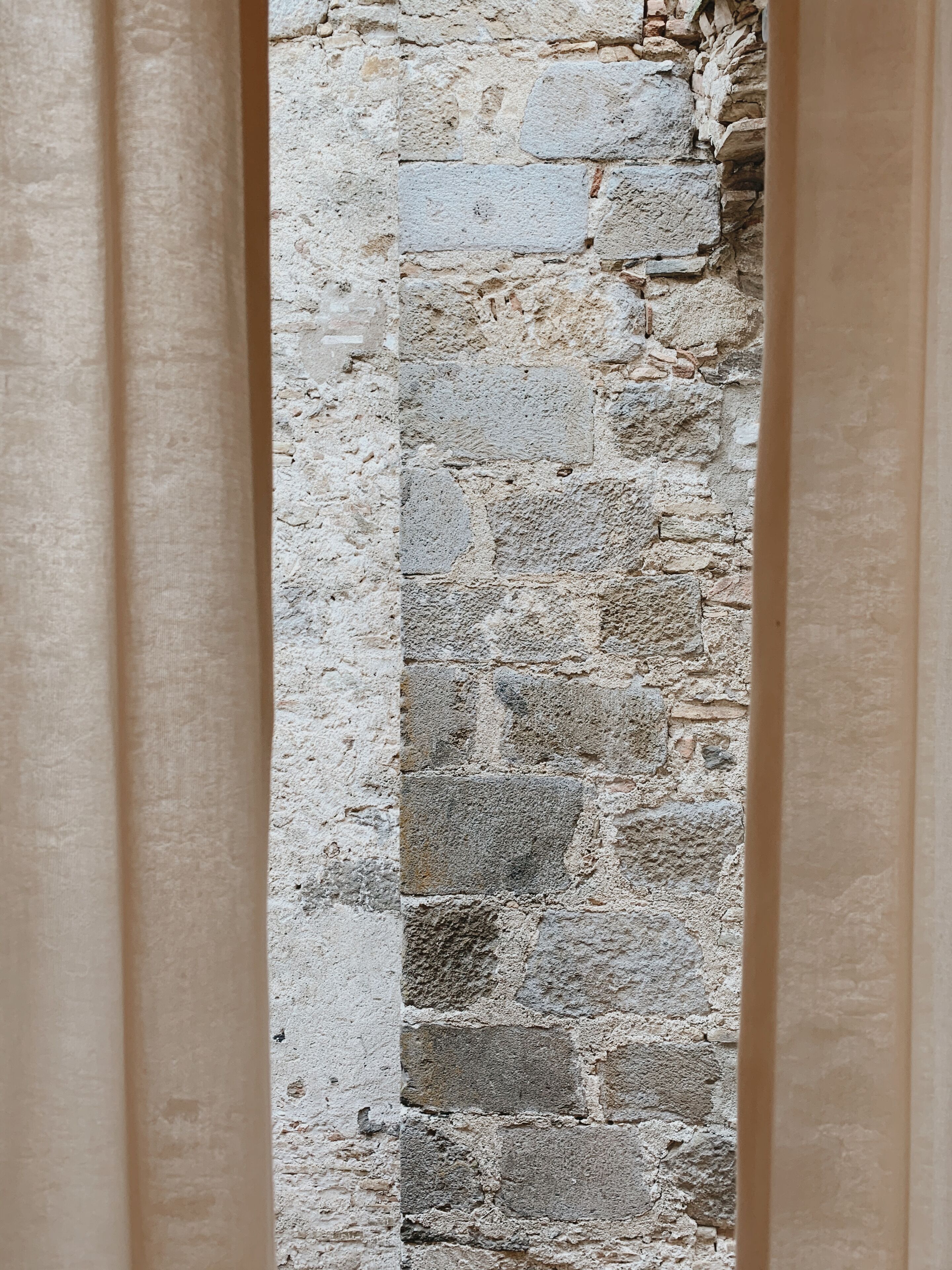A stone wall with a rough texture and irregularly shaped stones.