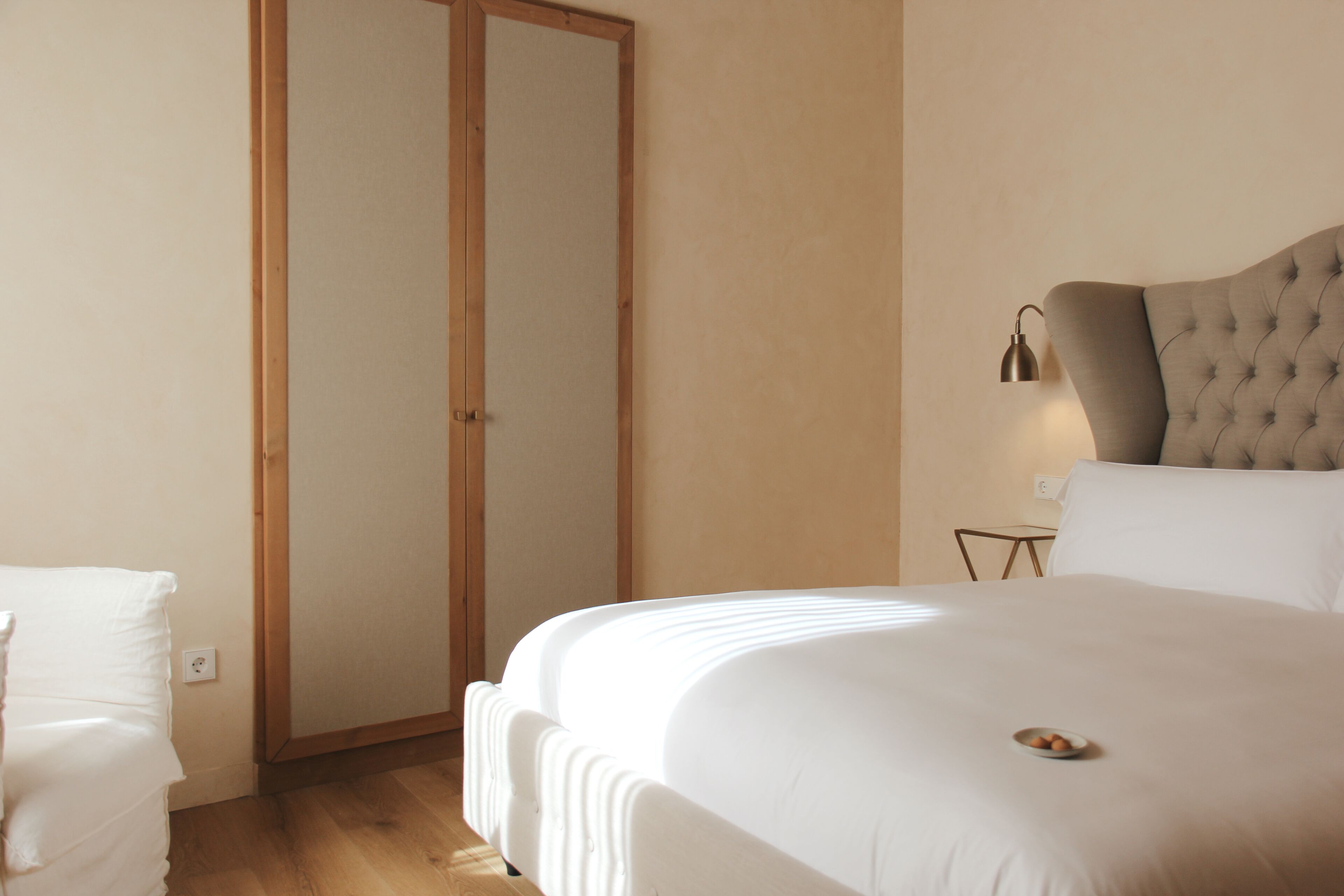 Un dormitorio con una cama grande, un armario y una mesita de noche con lámpara.