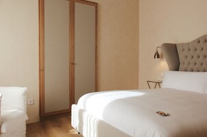 A bedroom with a large bed, a wardrobe, and a bedside table with a lamp.