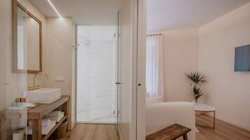A modern bathroom with a glass shower enclosure, a wooden vanity with a sink, and a small stool.