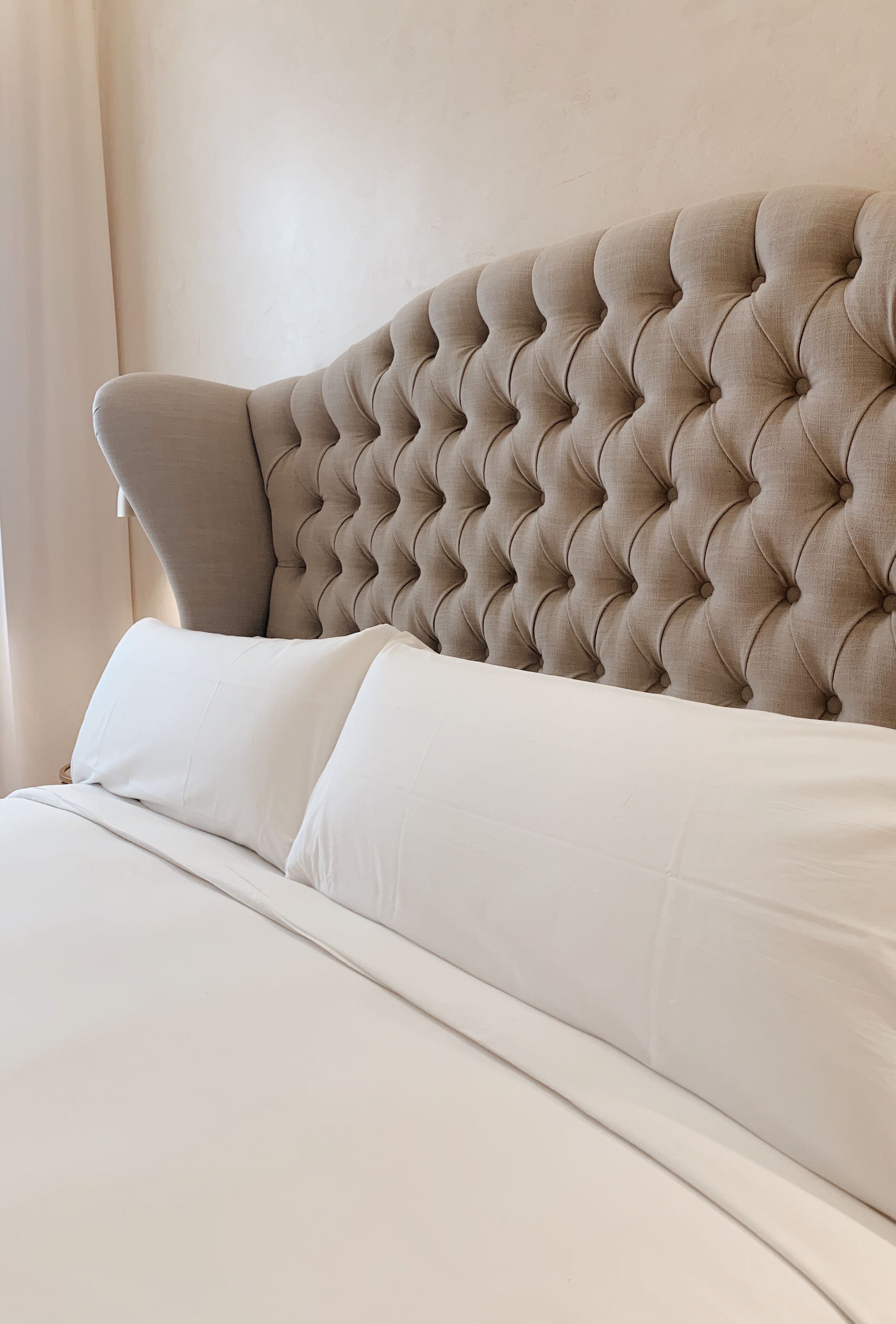 A bed with a tufted headboard and white bedding.