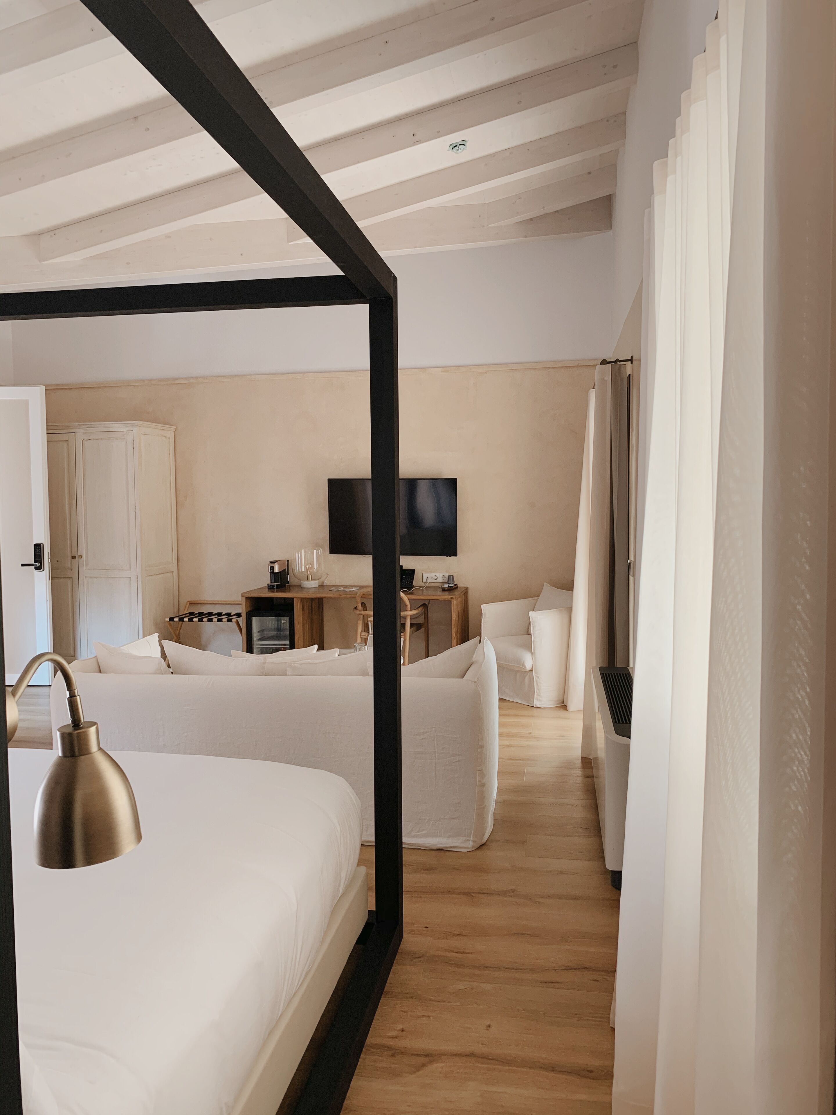 Ein Hotelzimmer mit einem großen Bett, einem Schreibtisch mit Fernseher, einem Sessel und einem Kleiderschrank.