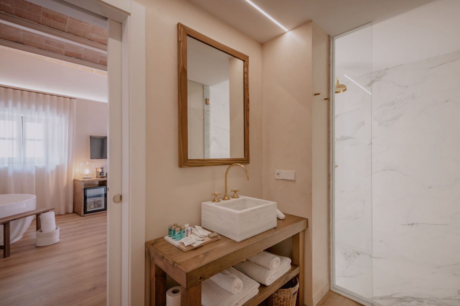 Un baño moderno con ducha de mármol, tocador de madera con lavamanos y espejo superior.