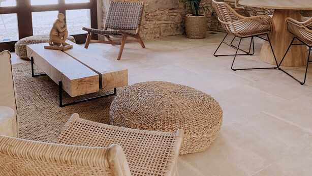 A spacious room with a stone wall, large windows, wicker furniture, and a potted plant. - Palau Macelli (Castello d'Empuries)