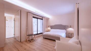 Un dormitorio con una cama grande, una mesita de noche, un perchero y una ventana con cortinas.