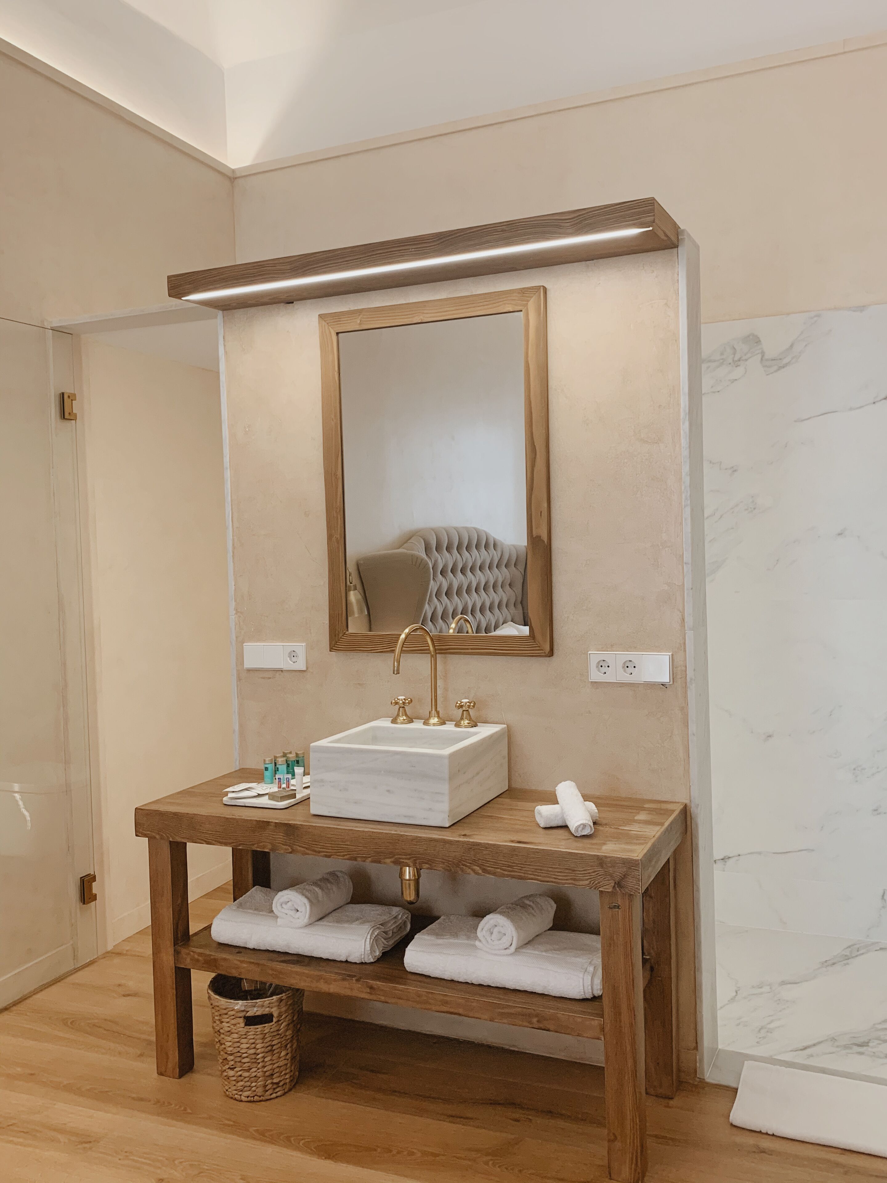 Un baño con tocador de madera, salpicadero de mármol y un espejo grande.