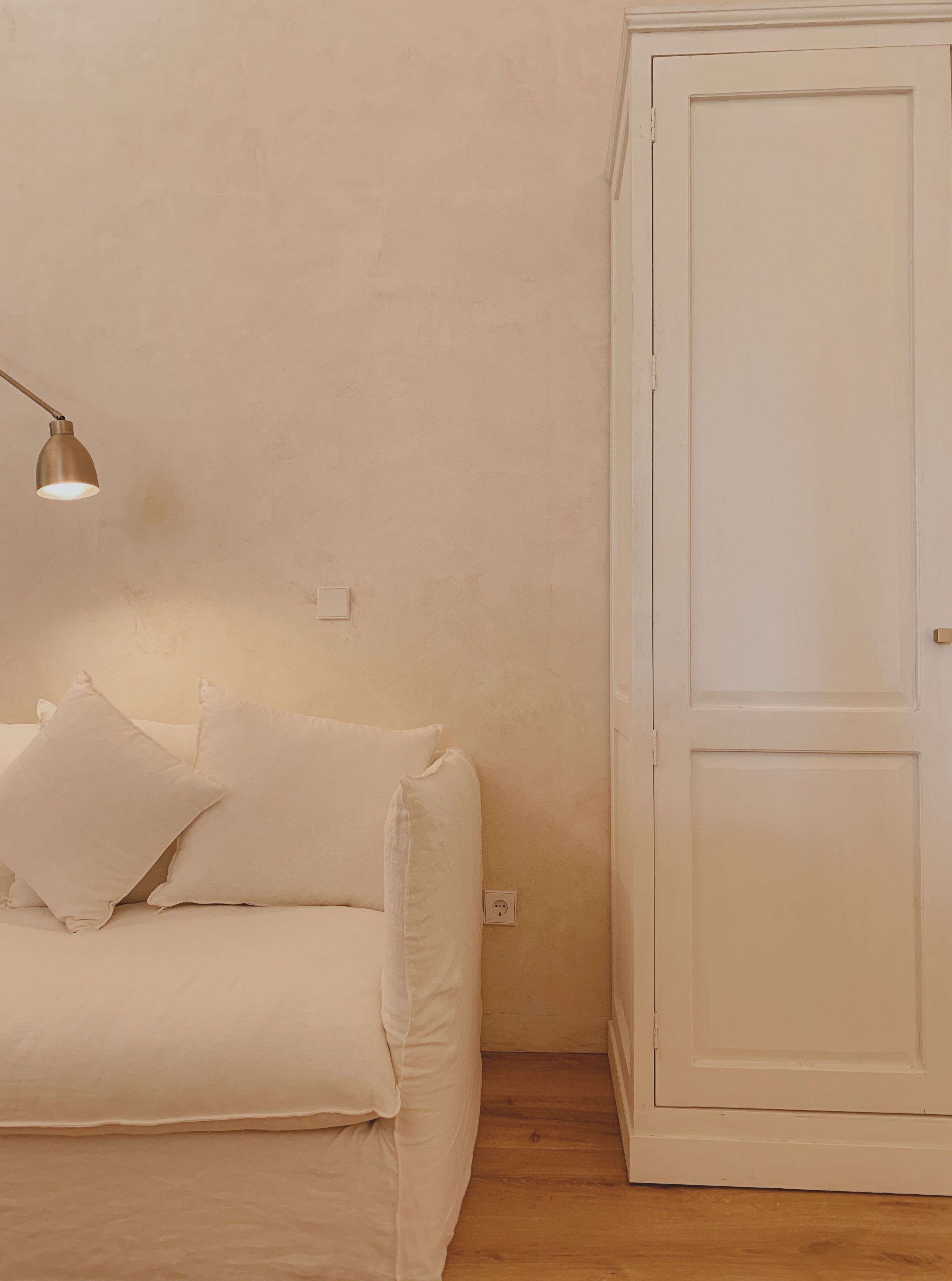 Una habitación con un sofá blanco, una lámpara y una puerta blanca.