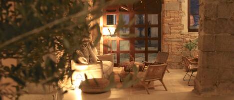 Un salon confortable avec un canapé, des fauteuils et une lampe. Une grande fenêtre offre une vue sur l’extérieur.