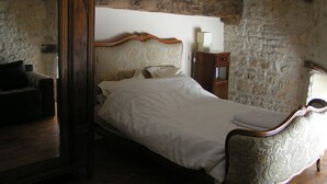Un dormitorio con una cama de madera, paredes de piedra y un espejo.