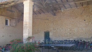 Un espacio al aire libre cubierto con un muro de piedra, un pilar y una fila de bicicletas.