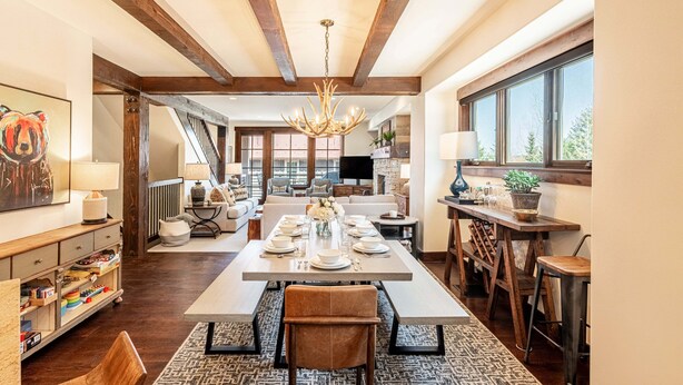 Uma sala de jantar espaçosa, com uma mesa grande, cadeiras de madeira e um candelabro.