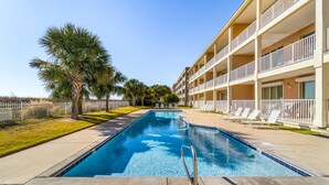 A swimming pool with a clear blue water, surrounded by a white fence, and adjacent to a multi-story building with balconies. - Dauphin Island Beach Club 310B Budget Friendly near the Beach!! (Dauphin Island)