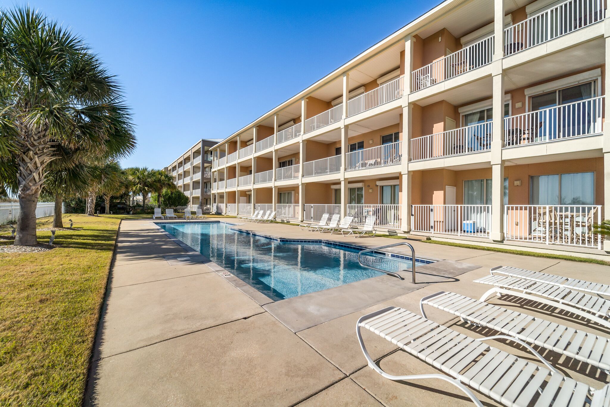 A hotel with a swimming pool, multiple balconies, and outdoor seating areas.