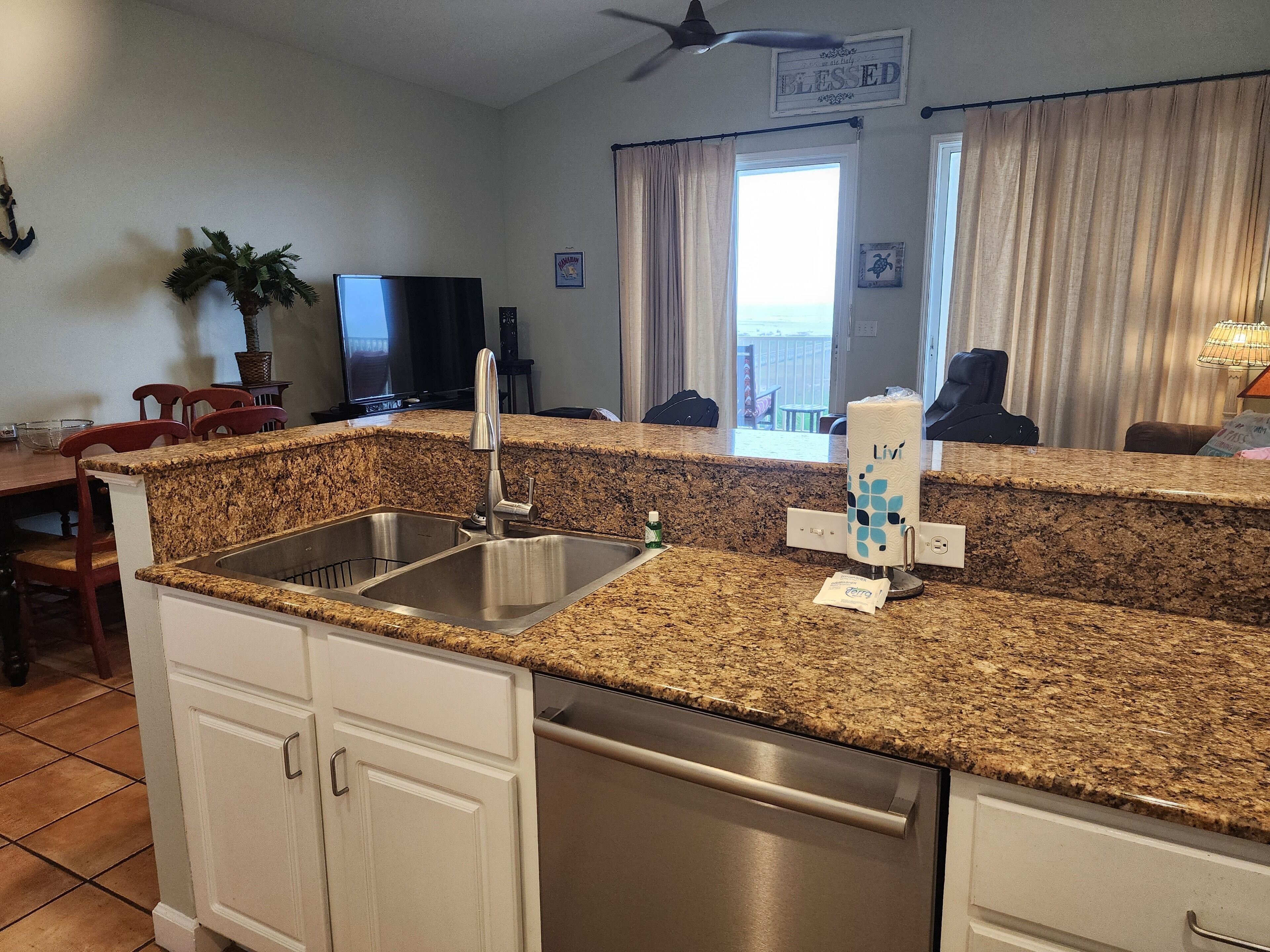 A kitchen with granite countertops, stainless steel appliances, and a view of the ocean through large windows.