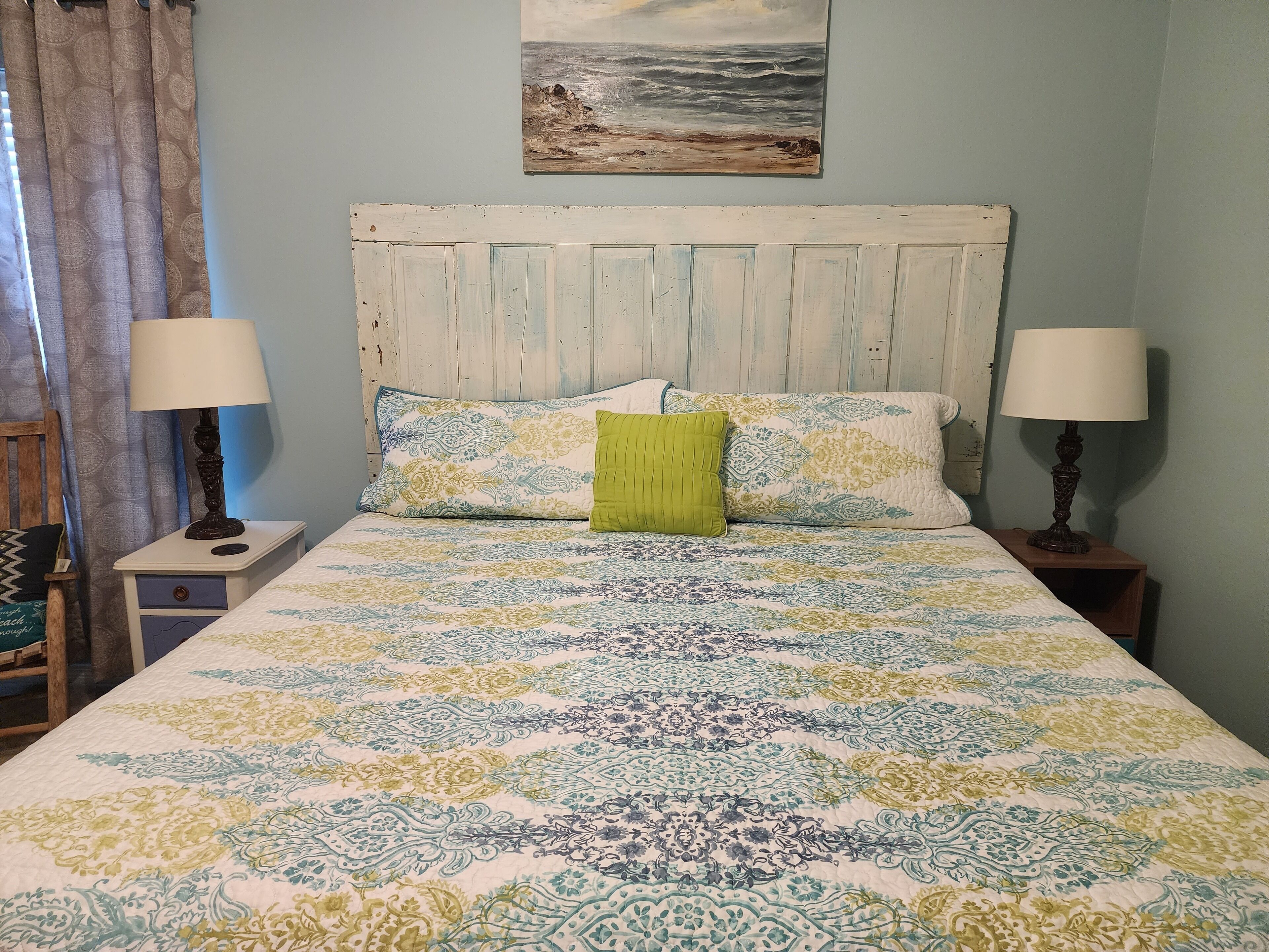 A bed with a patterned bedspread, two bedside lamps, and a headboard.