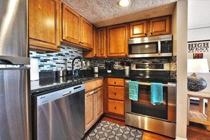 Una cocina moderna con electrodomésticos de acero inoxidable, armarios de madera y salpicadero de azulejos.