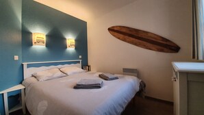 A bedroom with a bed, a wall-mounted surfboard, and a small heater.