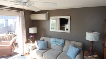 A living room with a sofa, two lamps, a ceiling fan, and a window.