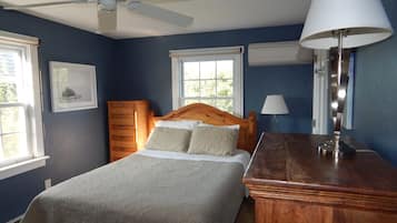 Ein Schlafzimmer mit Bett, Schminktisch, Deckenventilator und Fenstern.
