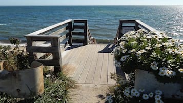 Un molo di legno che conduce a una spiaggia, con un cartello che recita 'THIS IS YOUR OWN RIDE'.