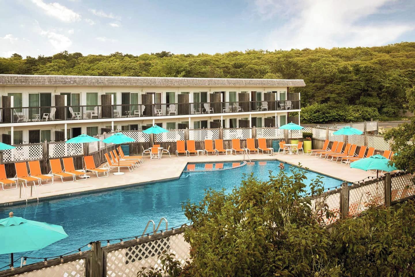 A hotel with a pool area, outdoor seating, and a building with balconies.