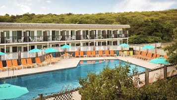 A hotel with a pool area, outdoor seating, and a building with balconies.