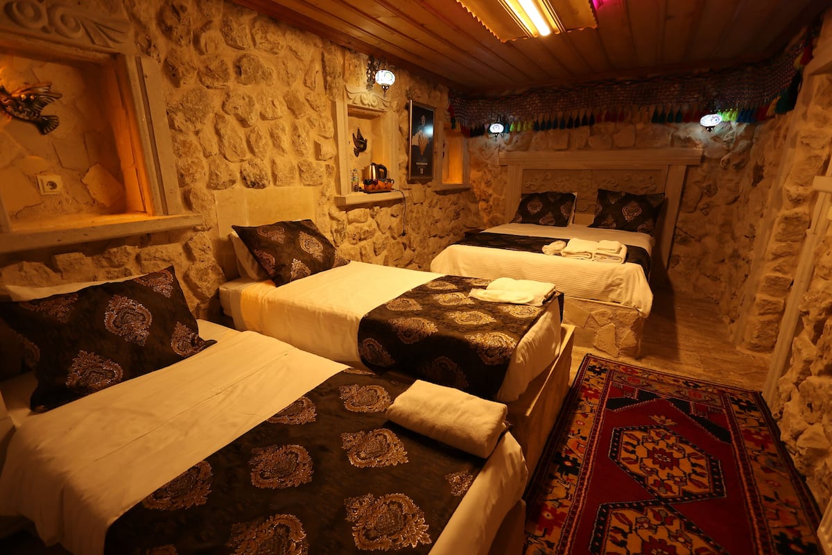A stone-walled room with two beds, each with patterned bedding and pillows.