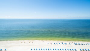A beach with rows of blue umbrellas and white sand.