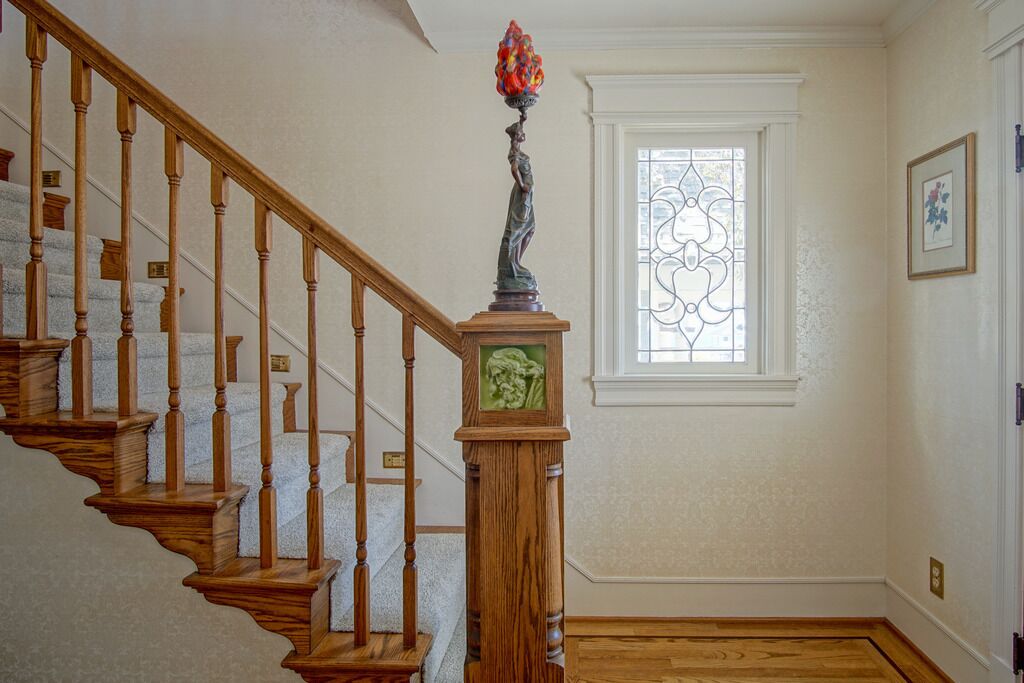 Una escalera de madera con un jarrón decorativo en la barandilla.