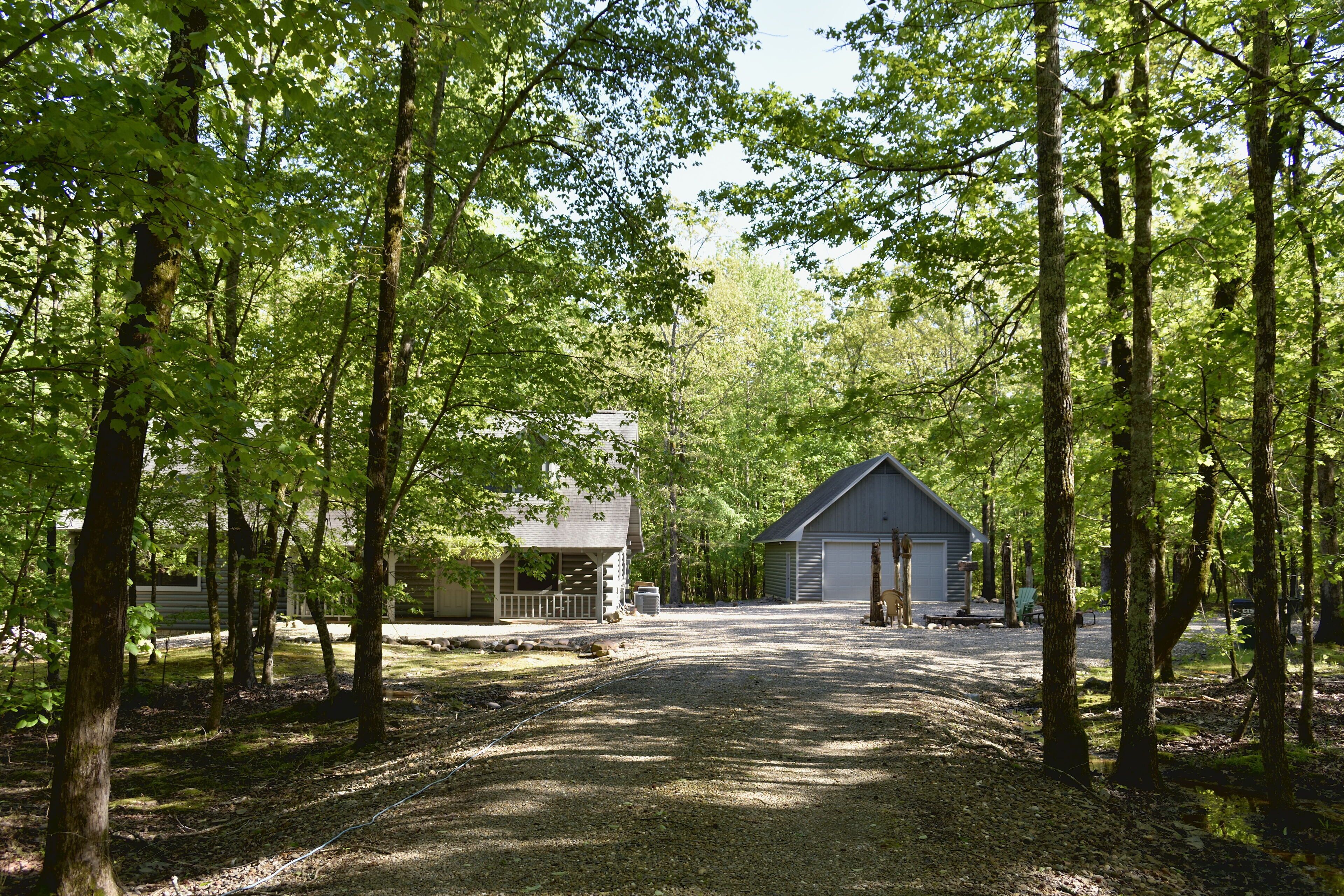 Une allée de gravier mène à un bâtiment entouré d’arbres.