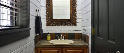 Un baño con tocador de madera, lavamanos y espejo con marco decorativo.