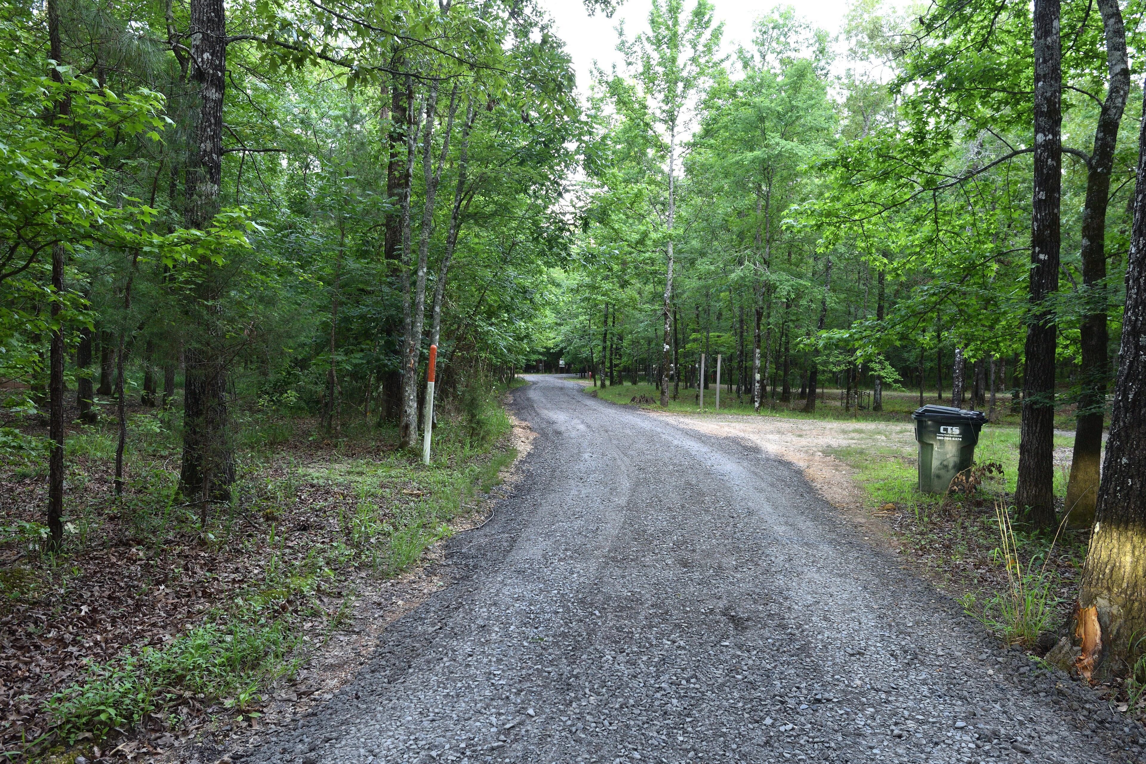 A gravel road in a forested area with trees on both sides.