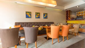 A modern hotel lobby with a sofa, chairs, a bar area, and artwork on the wall. - Villa Akacija (Belgrade)
