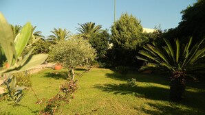 A well-maintained garden with a variety of trees and shrubs, a lawn, and a clear sky. - Le Quattro Lune (Orosei)