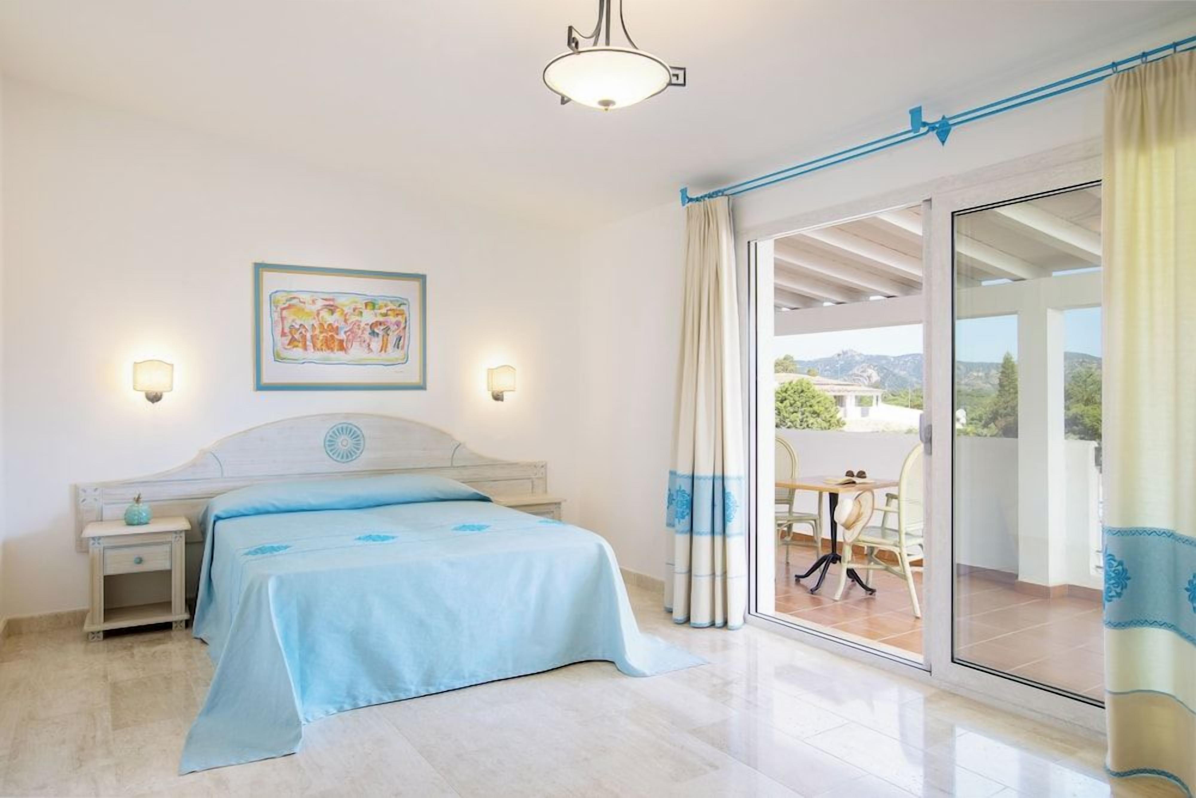 Une chambre à coucher avec un lit, des tables de chevet, une fenêtre avec des rideaux et une vue sur l’extérieur.