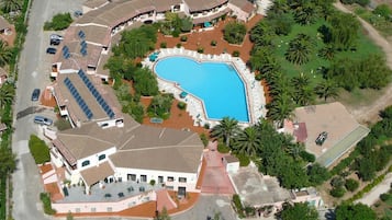 Una vista aerea di un resort con piscina, diversi edifici e un'area parcheggio.