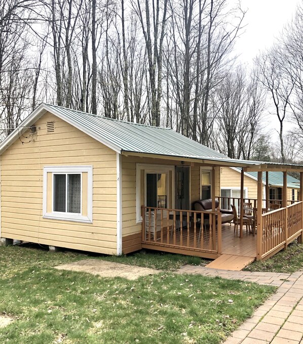 Eine kleine, eingeschossige Hütte mit Veranda und einer Terrasse.